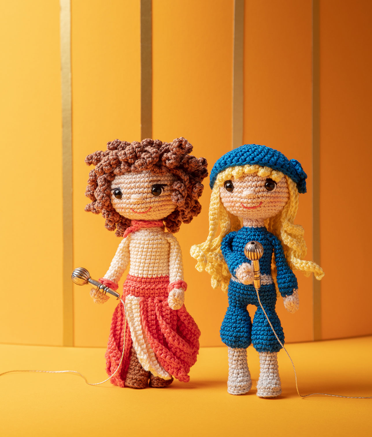 inszeniertes Foto einer Agneta und einer Frida Häkelpuppe (Abba) mit Mikrophonen in der Hand auf einer orangen Bühne für ein Promi-Häkelbuch