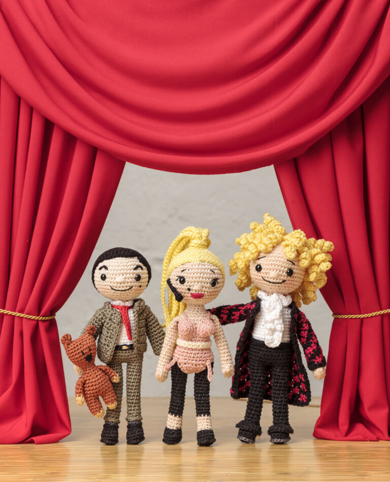 Titelfoto für ein Promi-Häkelbuch mit drei Häkelfiguren - Mr.Bean, Madonna ? Thomas Gottschalk - vor einem roten Bühnenvorhang
