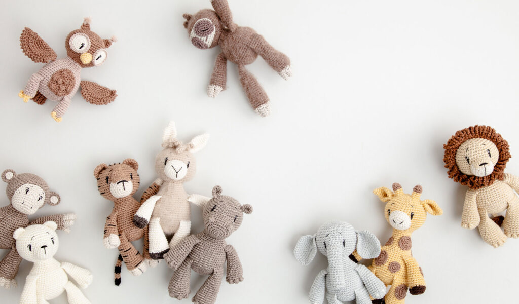 Flatlay Foto mit mehreren Häkelpuppen arrangiert auf hellgrauem Hintergrund für ein Häkelbuch