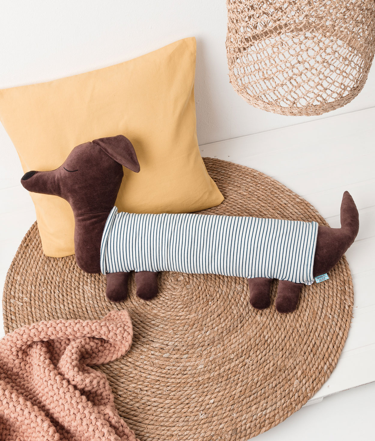 Produktfoto eines selbstgenähten Dackel-Kissens in einer Interior-Kulisse mit Kissen, Teppich, Lampenschirm und einer weichen Decke