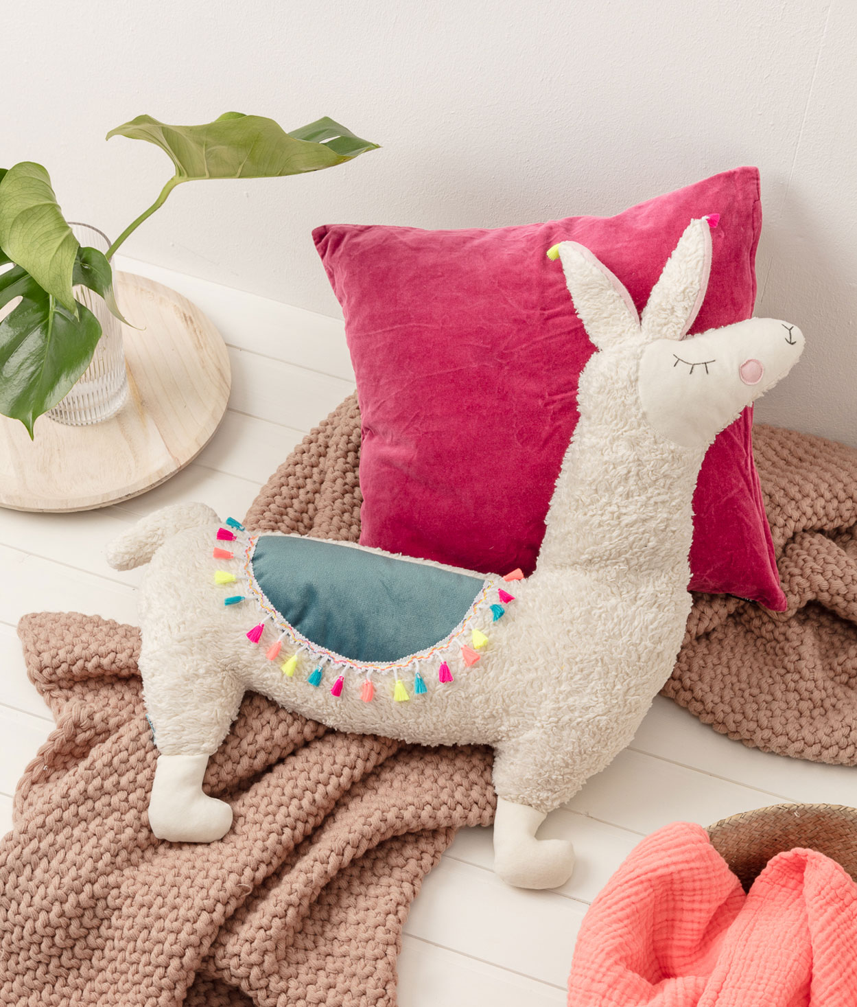 Produktfoto eines selbstgenähten Lama-Kissens in einer Interior-Kulisse mit Kissen, Pflanzen und einer weichen Decke