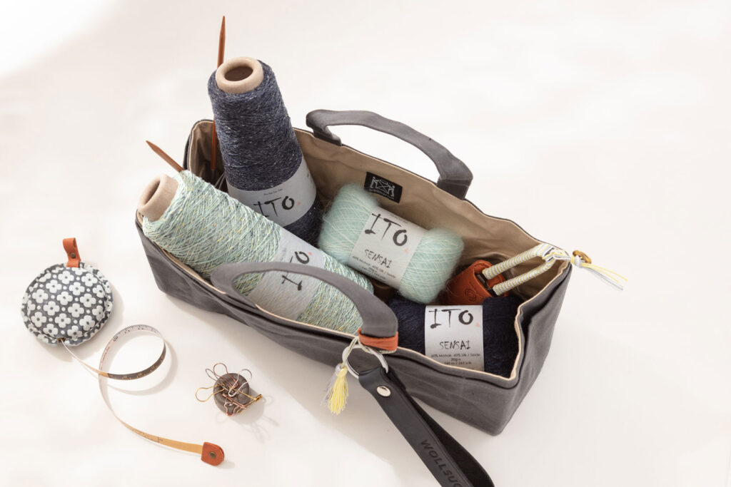 Produktfoto einer Projekttasche gefüllt mit mehreren Knäuel und Konen von ITO und verschiedenem Strickzubehör