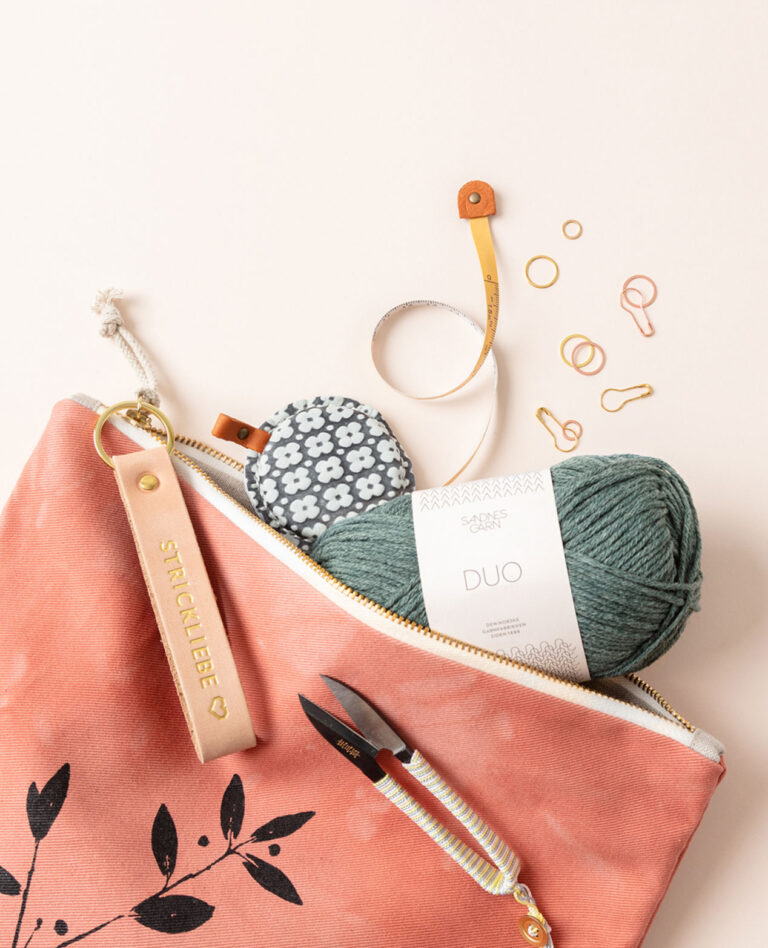 Titelfoto für die Fotoproduktion eines Bilderpools zum Thema Stricken, das eine Projekttasche mit Wolle und verschiedenem Strickzubehör zeigt