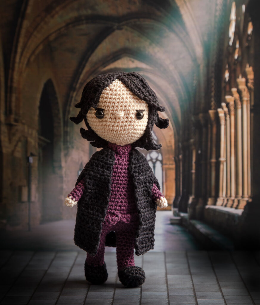 Produktfoto einer Snape Häkelfigur aus Harry Potter in nachgestellter Mini-Kulisse eines dunklen Gangs von Hogwarts