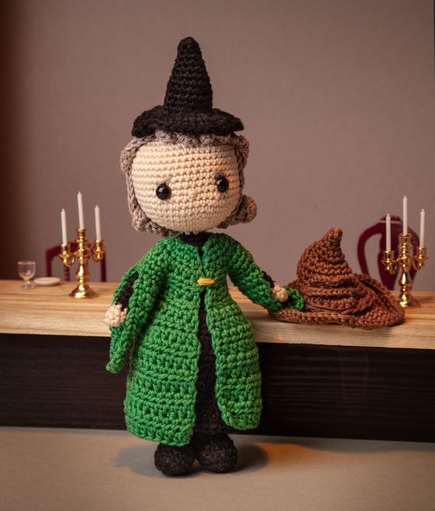 Produktfoto einer McGonagall Häkelfigur aus Harry Potter in nachgestellter Mini-Kulisse des Speisesaals mit Esstisch, Kerzenleuchtern und dem sprechenden Hut