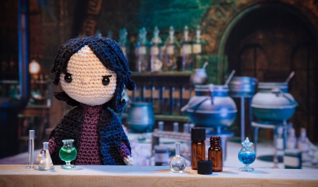 Produktfoto einer Severus Snape-Häkelfigur aus Harry Potter in nachgestellter Mini-Kulisse eines Zauberlabors